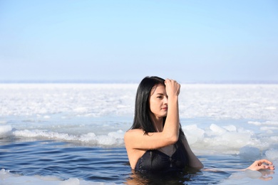 Photo of Woman immersing in icy water on winter day. Baptism ritual