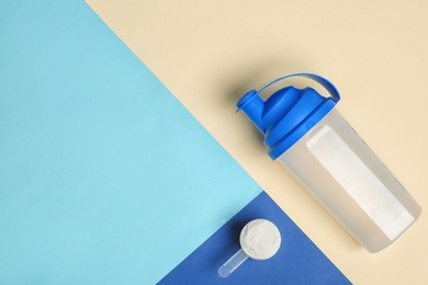 Photo of Flat lay composition with protein powder, bottle and space for text on color background. Preparing shake