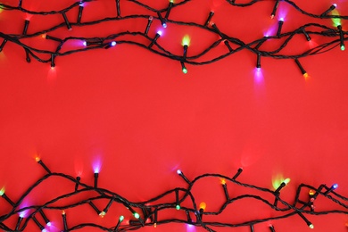 Photo of Glowing Christmas lights on color background, top view