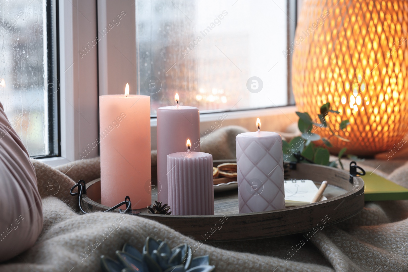 Photo of Tray with burning wax candles and decor on window sill indoors