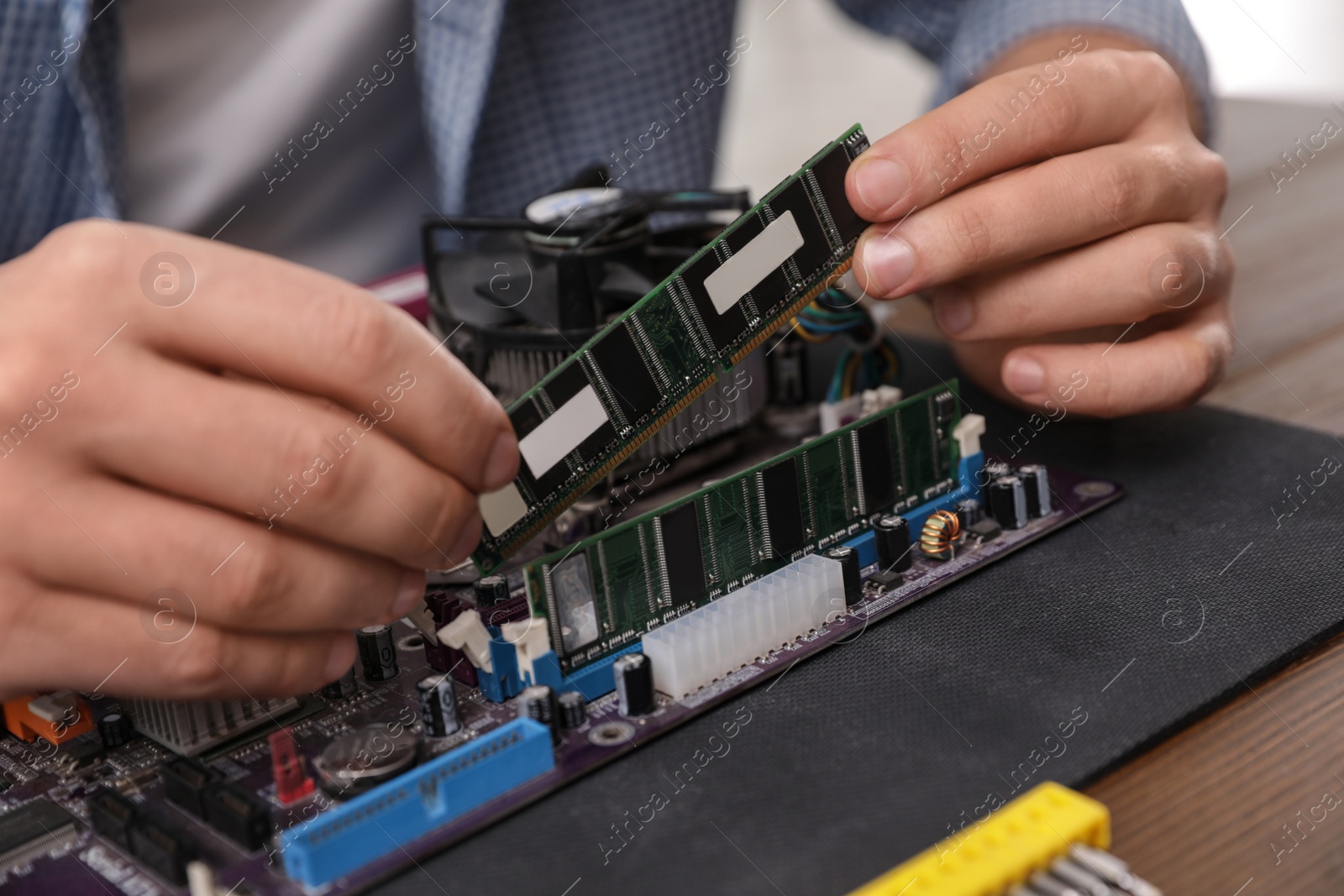 Photo of Male technician repairing motherboard at table, closeup