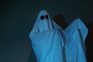 Photo of Creepy ghost. Woman covered with sheet in color light