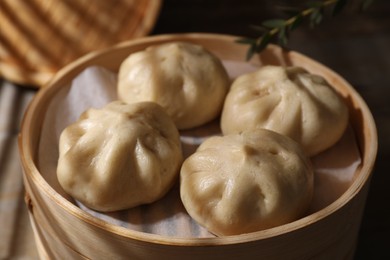 Photo of Delicious bao buns (baozi) in bamboo steamer, closeup