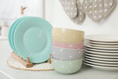 Clean plates and bowls on white countertop in kitchen