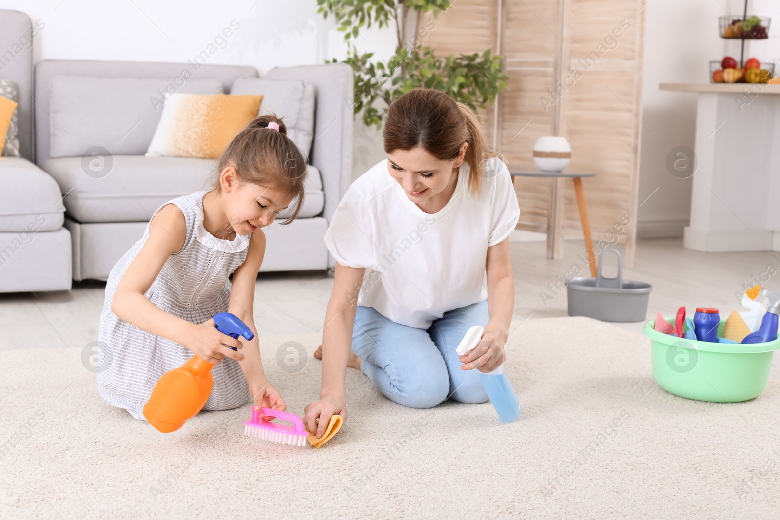 Photo of Housewife with daughter cleaning carpet in room together