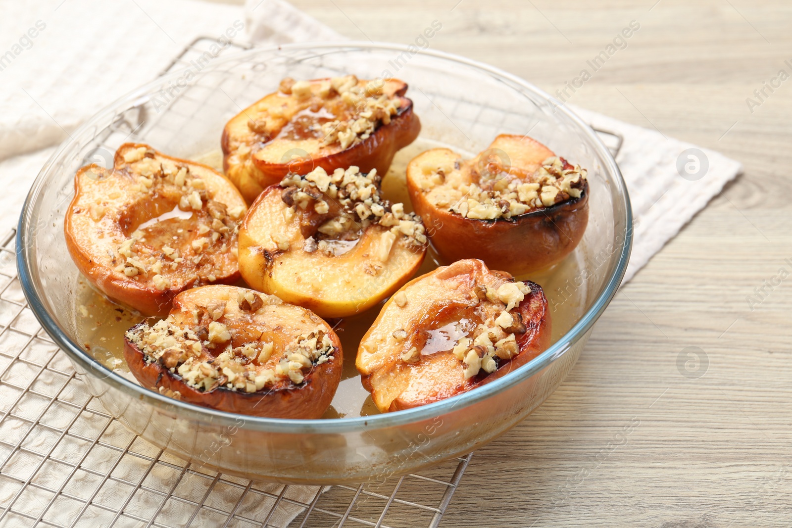 Photo of Delicious baked quinces with nuts and honey in bowl on wooden table, closeup