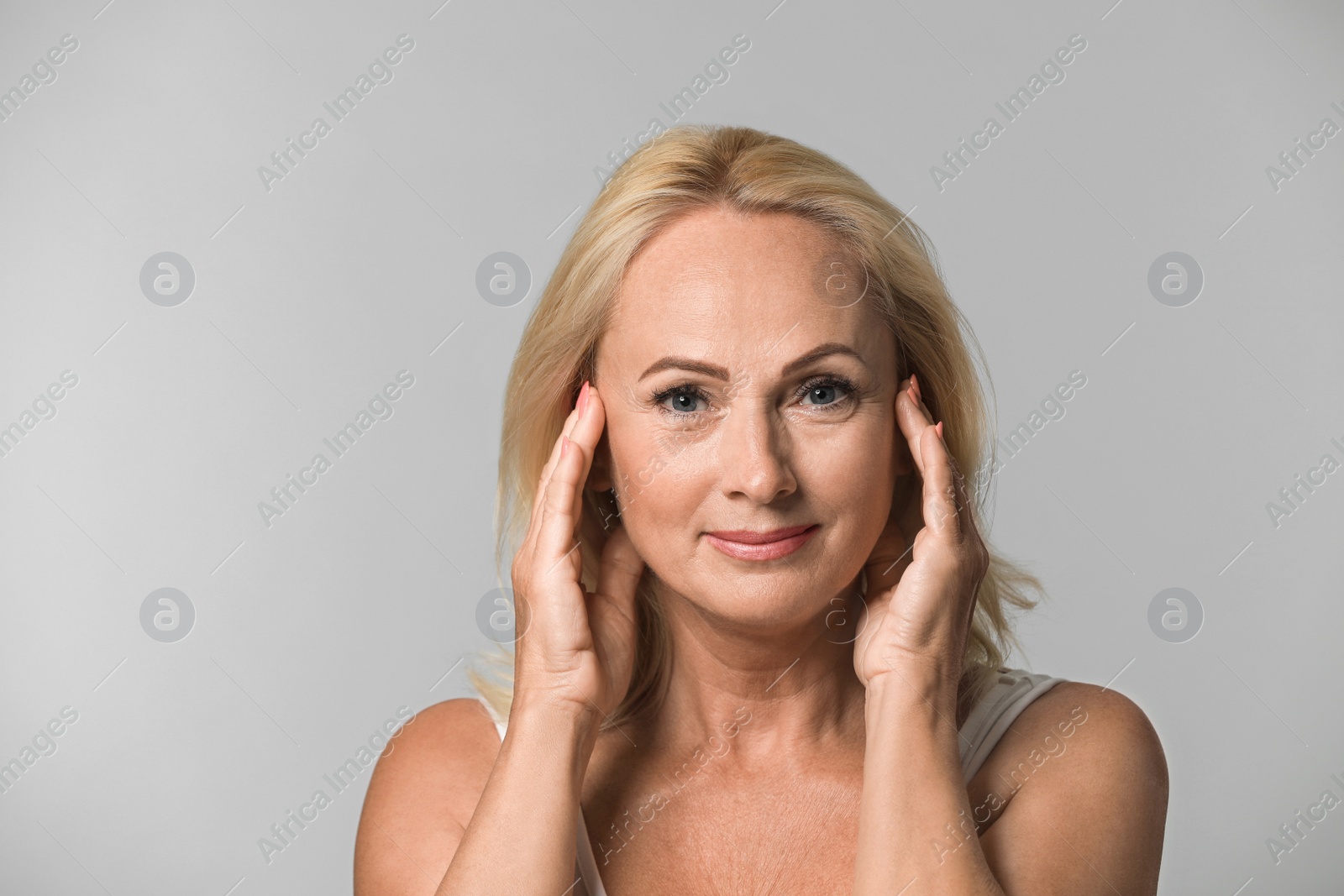 Photo of Portrait of beautiful mature woman with perfect skin on grey background