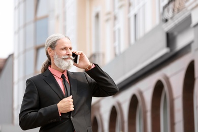 Photo of Handsome mature man in suit with mobile phone, outdoors