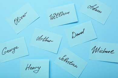 Choosing baby name. Paper stickers with different names on light blue background, flat lay