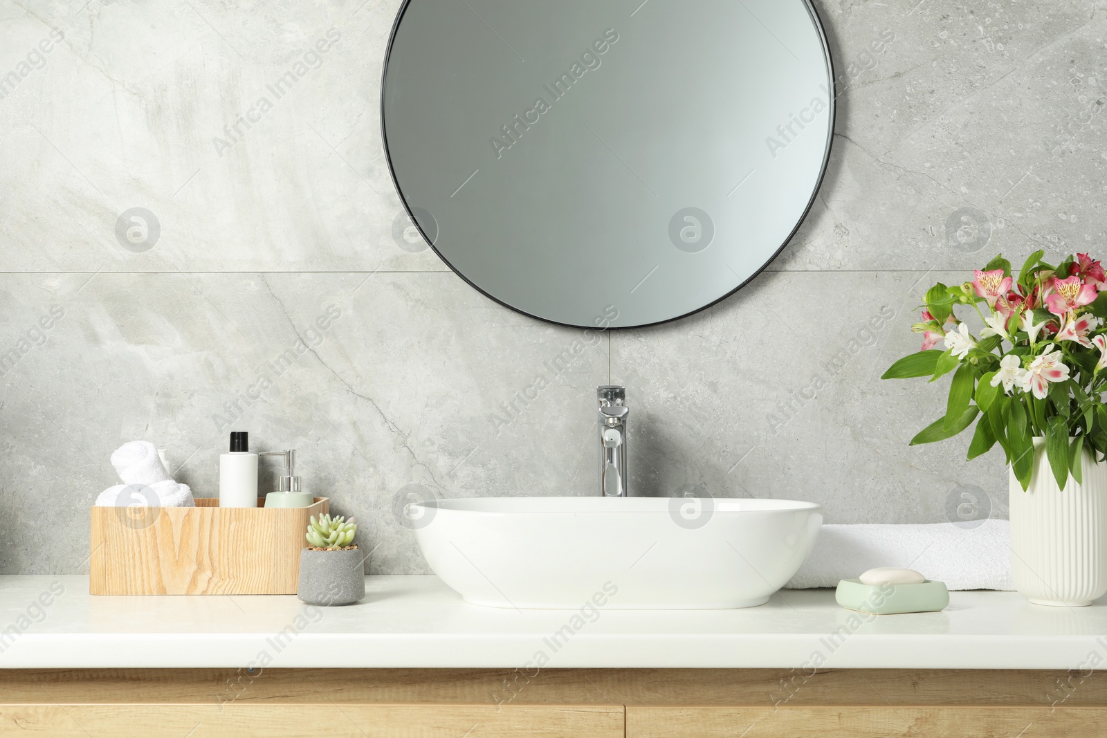 Photo of Vase with beautiful Alstroemeria flowers and toiletries near sink in bathroom