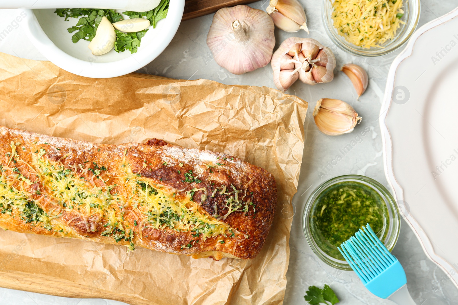 Photo of Tasty homemade garlic bread with cheese and herbs on grey table, flat lay