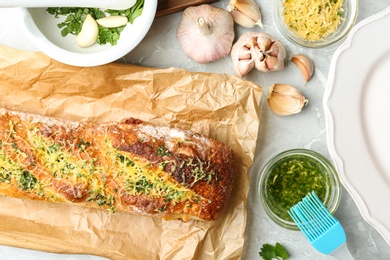 Photo of Tasty homemade garlic bread with cheese and herbs on grey table, flat lay