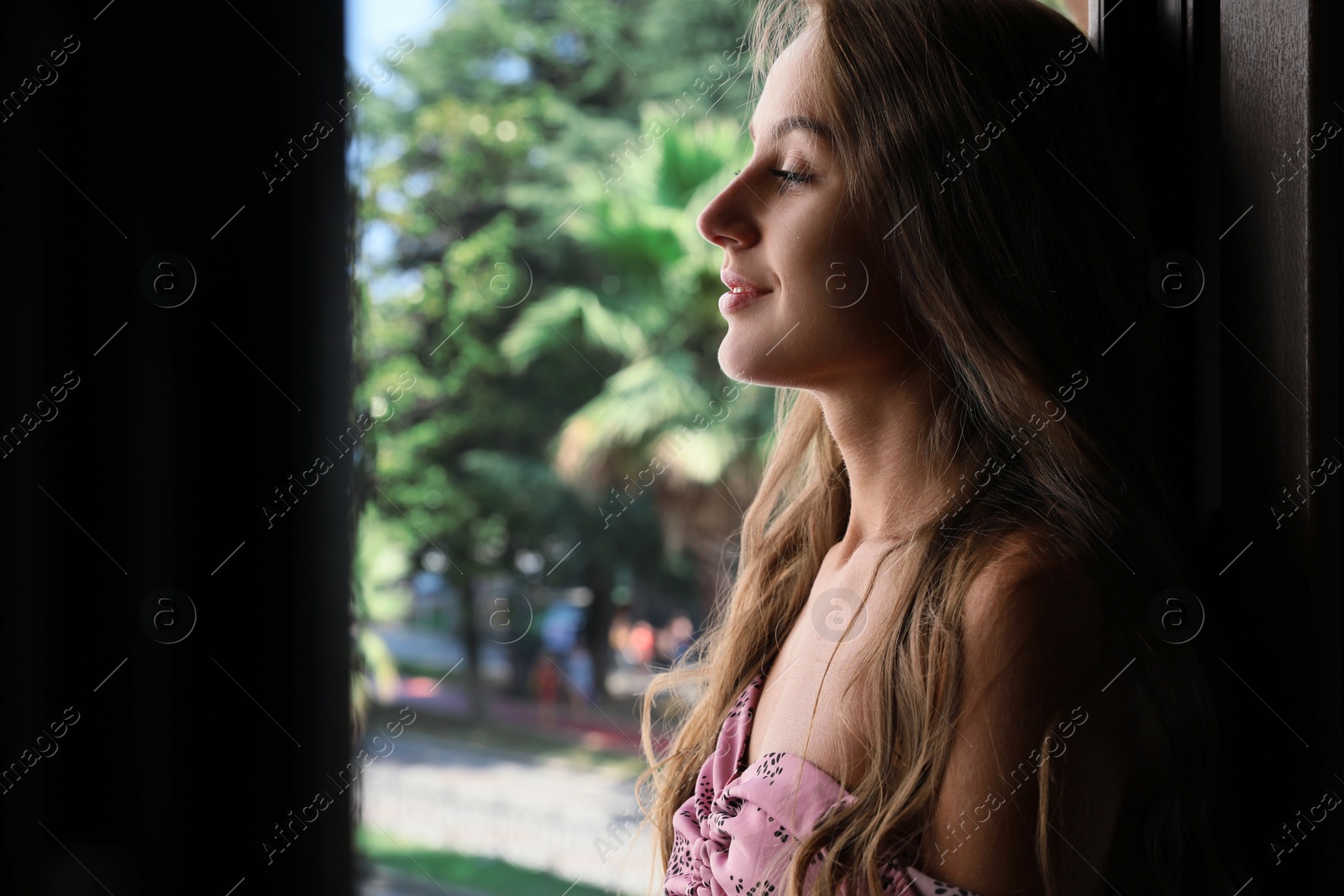 Photo of Beautiful young woman with long hair standing on balcony