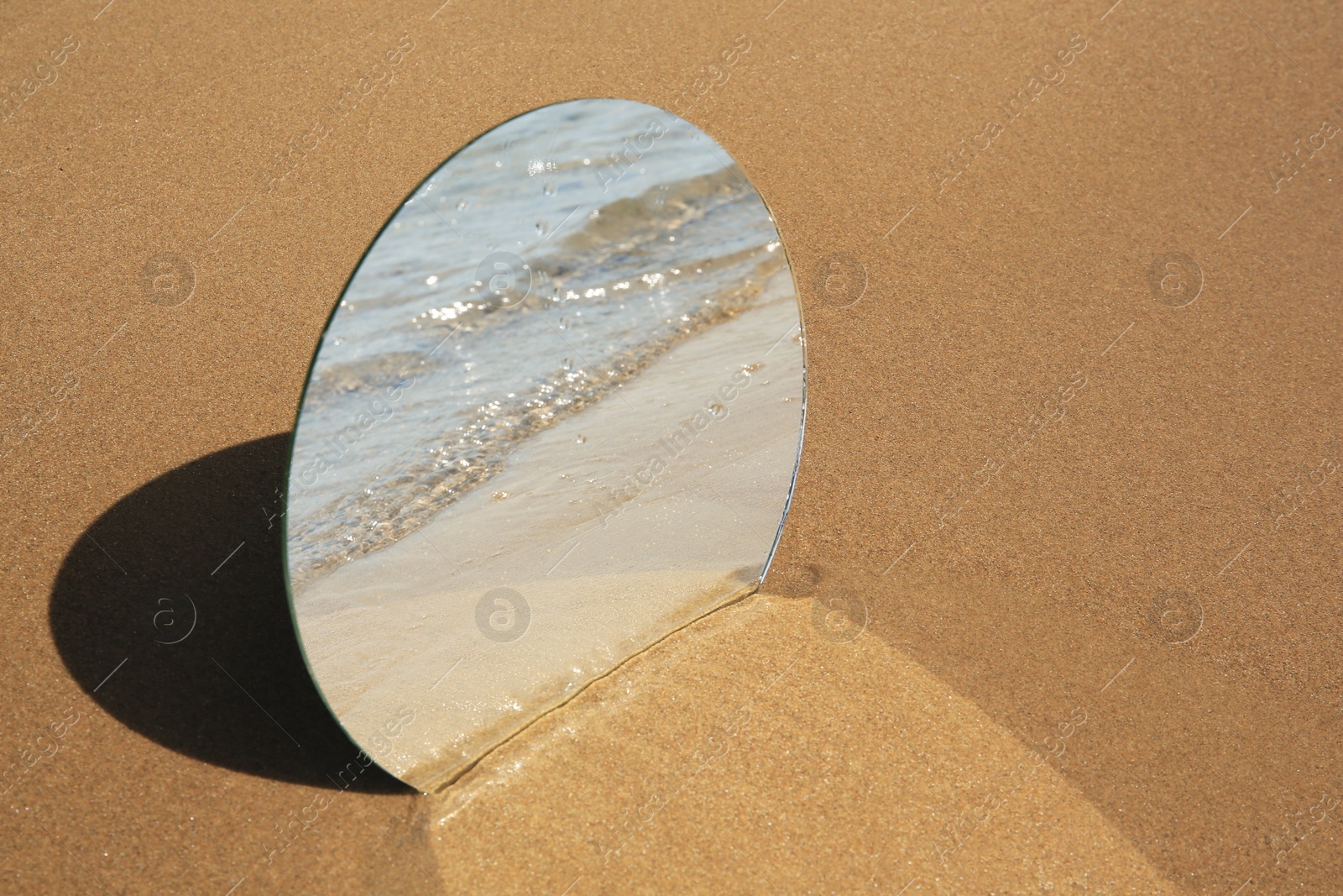 Photo of Round mirror reflecting sea on sandy beach