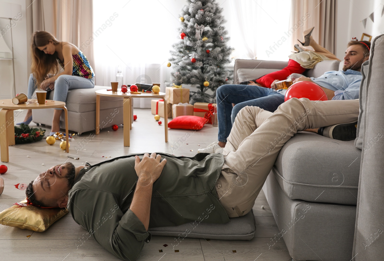 Photo of Friends suffering from hangover in messy room after New Year party