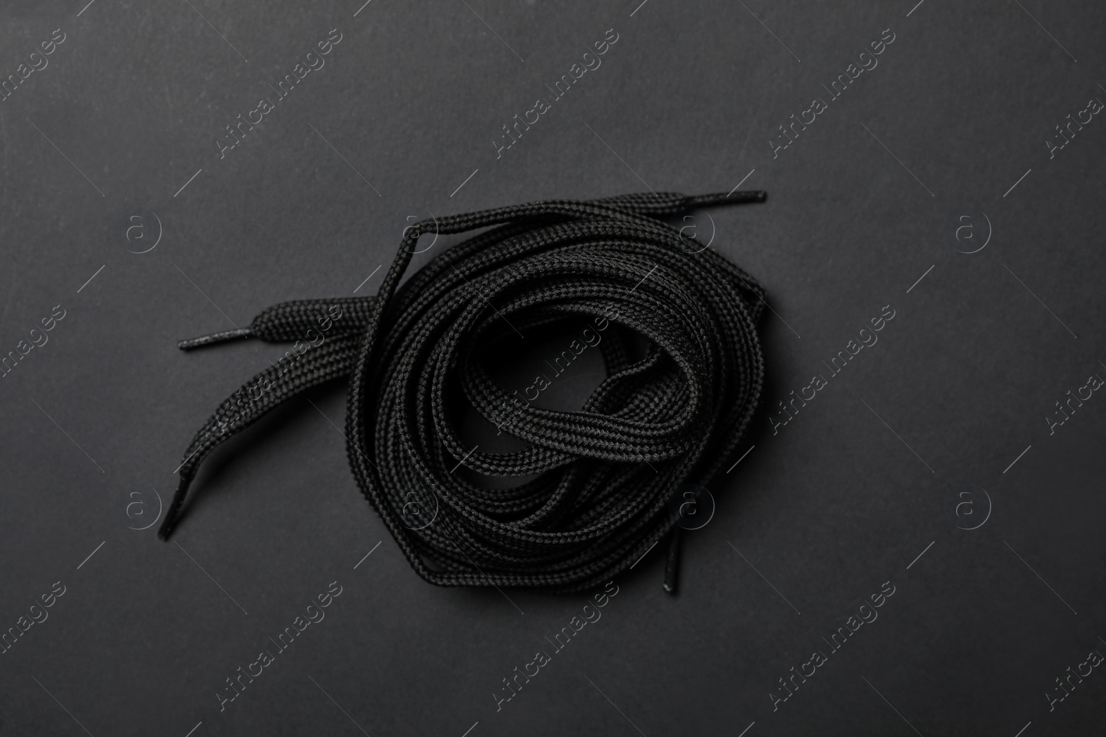 Photo of Shoelaces on black background, top view. Stylish accessory