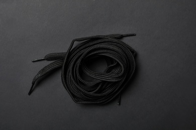 Photo of Shoelaces on black background, top view. Stylish accessory