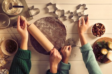 Photo of Mother and child making Christmas cookies at white wooden table together, top view