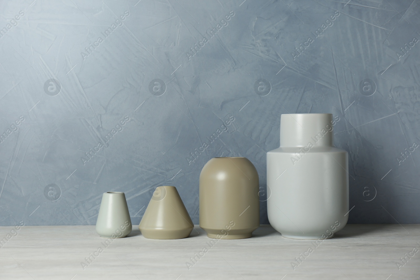 Photo of Beautiful ceramic vases on table against color wall. Space for text