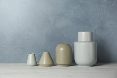 Photo of Beautiful ceramic vases on table against color wall. Space for text