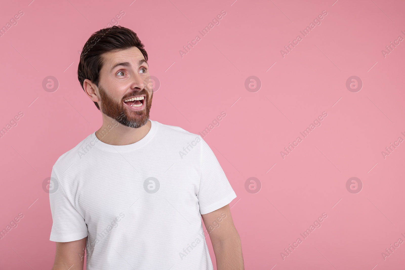 Photo of Portrait of happy surprised man on pink background, space for text