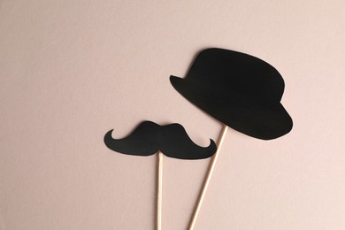 Fake paper mustache and hat with sticks on grey background, flat lay