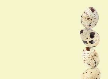 Image of Stacked speckled quail eggs on light beige background. Space for text