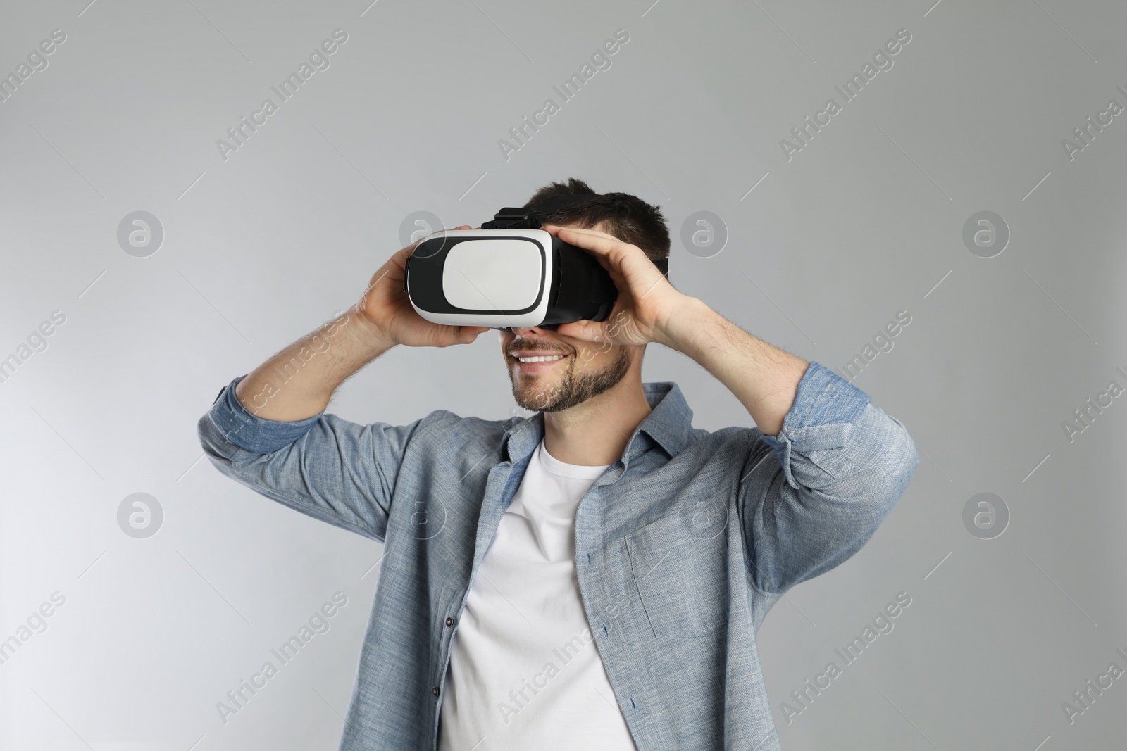 Photo of Man using virtual reality headset on grey background