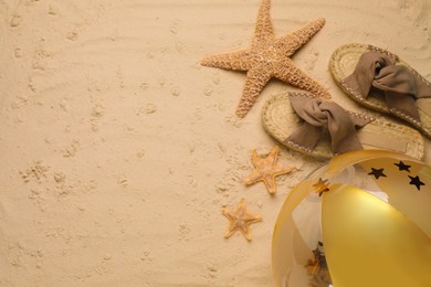 Photo of Beach ball, slippers and starfishes on sand, flat lay. Space for text