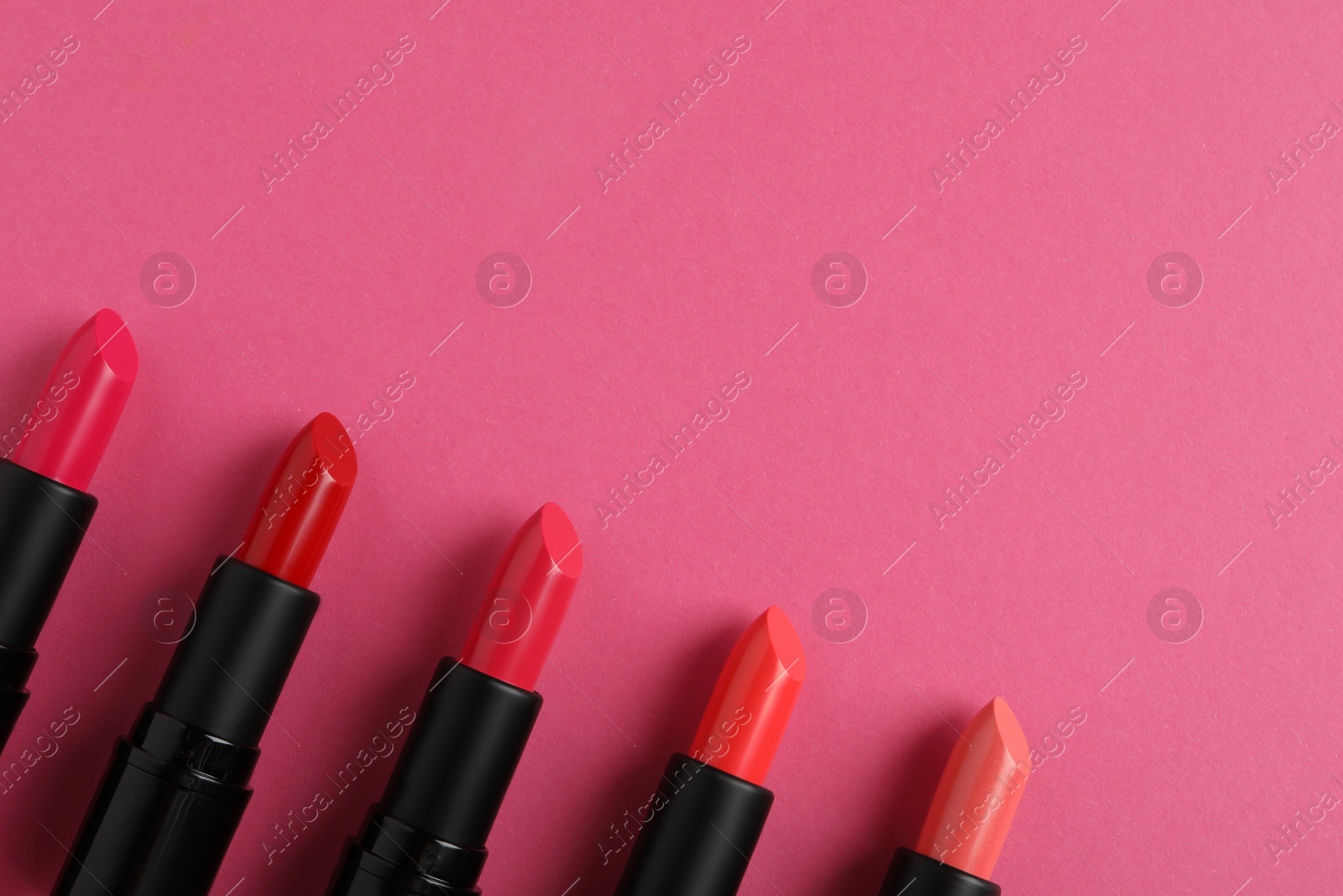 Photo of Beautiful lipsticks on pink background, flat lay. Space for text