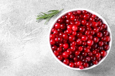 Fresh ripe cranberries in bowl on grey table, top view. Space for text