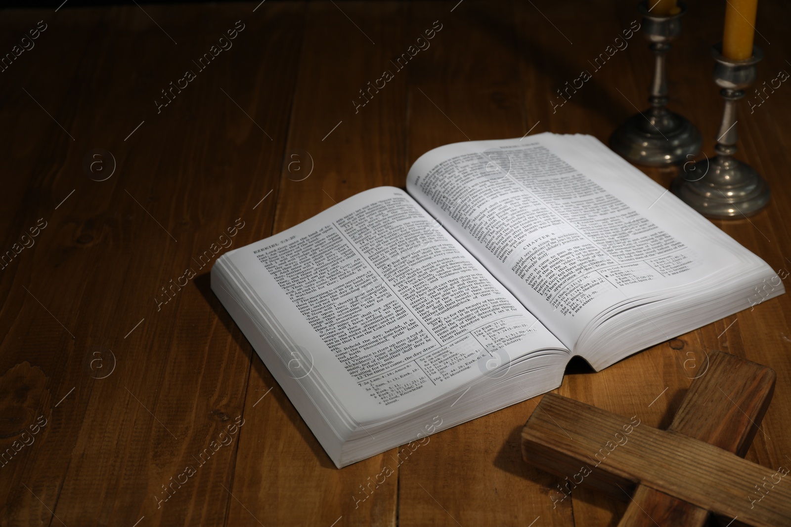 Photo of Bible, cross and church candles on wooden table