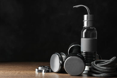 Photo of Gym equipment and accessories on floor against dark background. Space for text