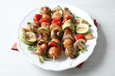 Photo of Delicious shish kebabs with vegetables and microgreens on white table, closeup