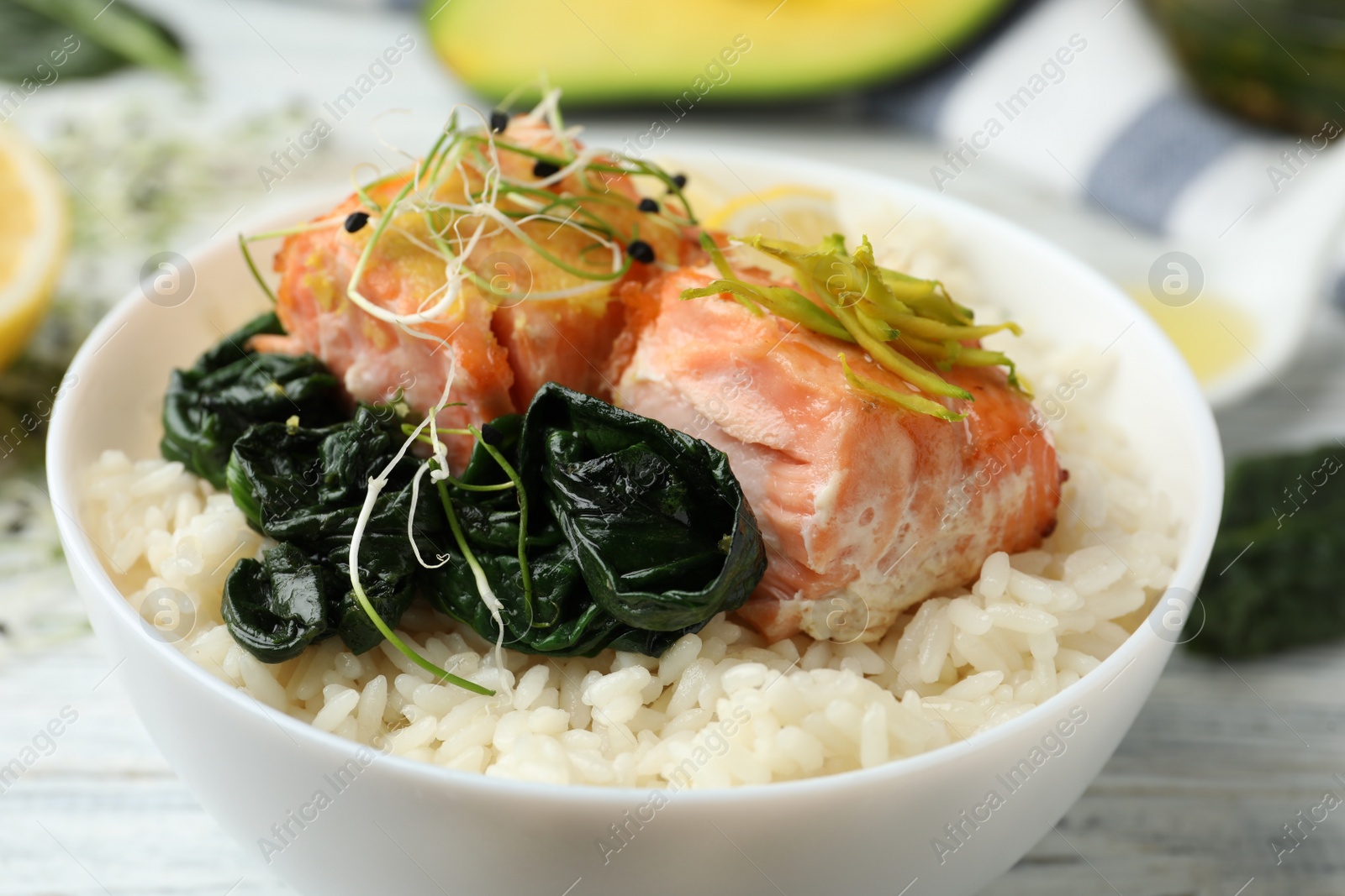 Photo of Tasty salmon with rice and spinach on white wooden table, closeup