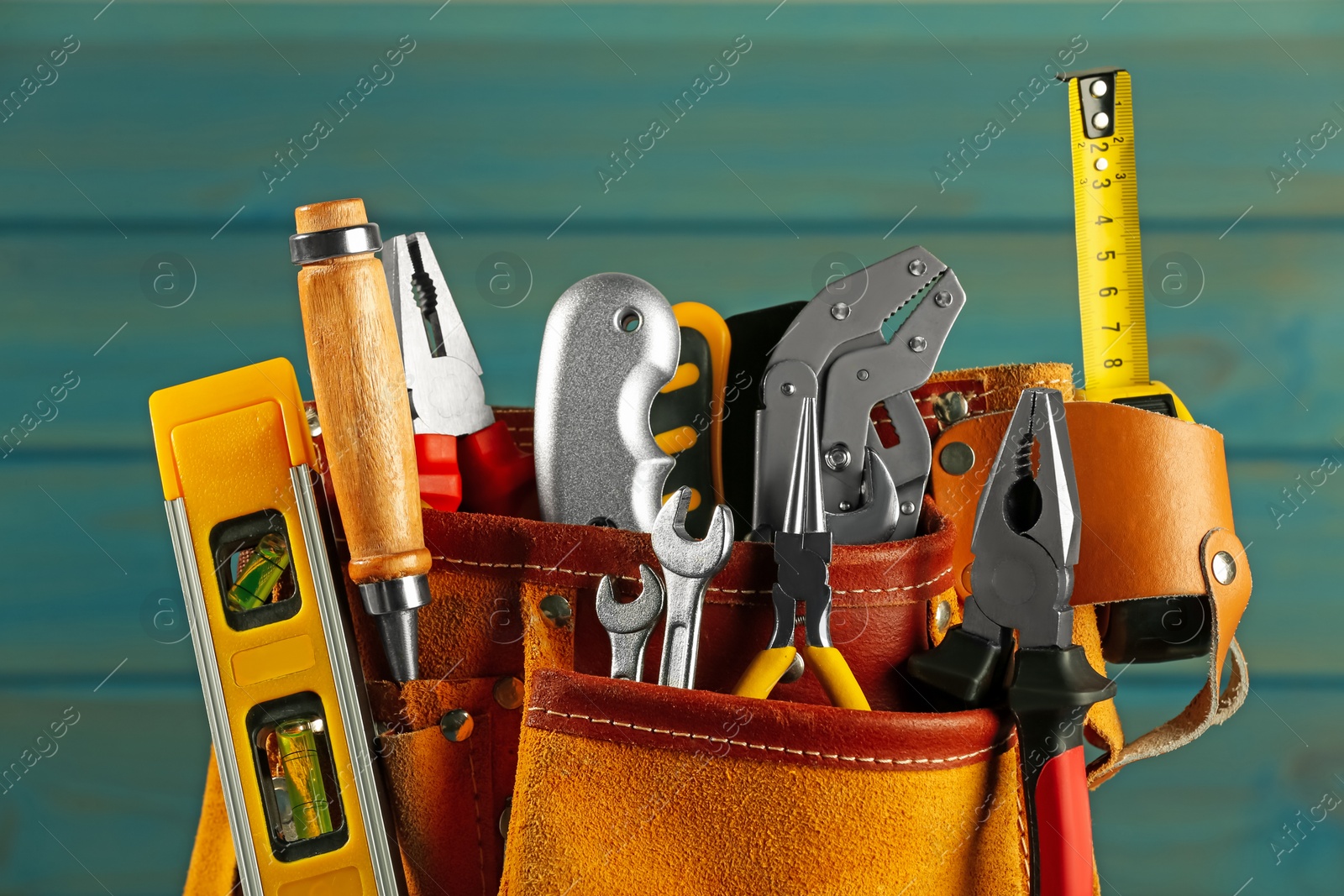 Photo of Belt with different tools on light blue wooden background, closeup