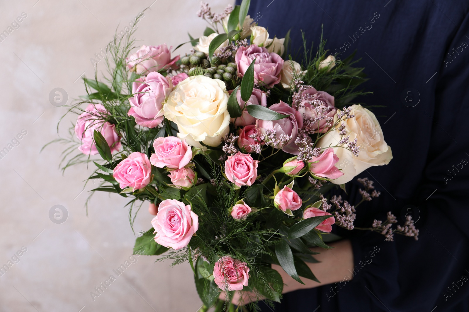 Photo of Woman with bouquet of beautiful roses on beige background, closeup