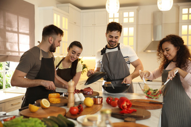Photo of Happy people cooking food together in kitchen