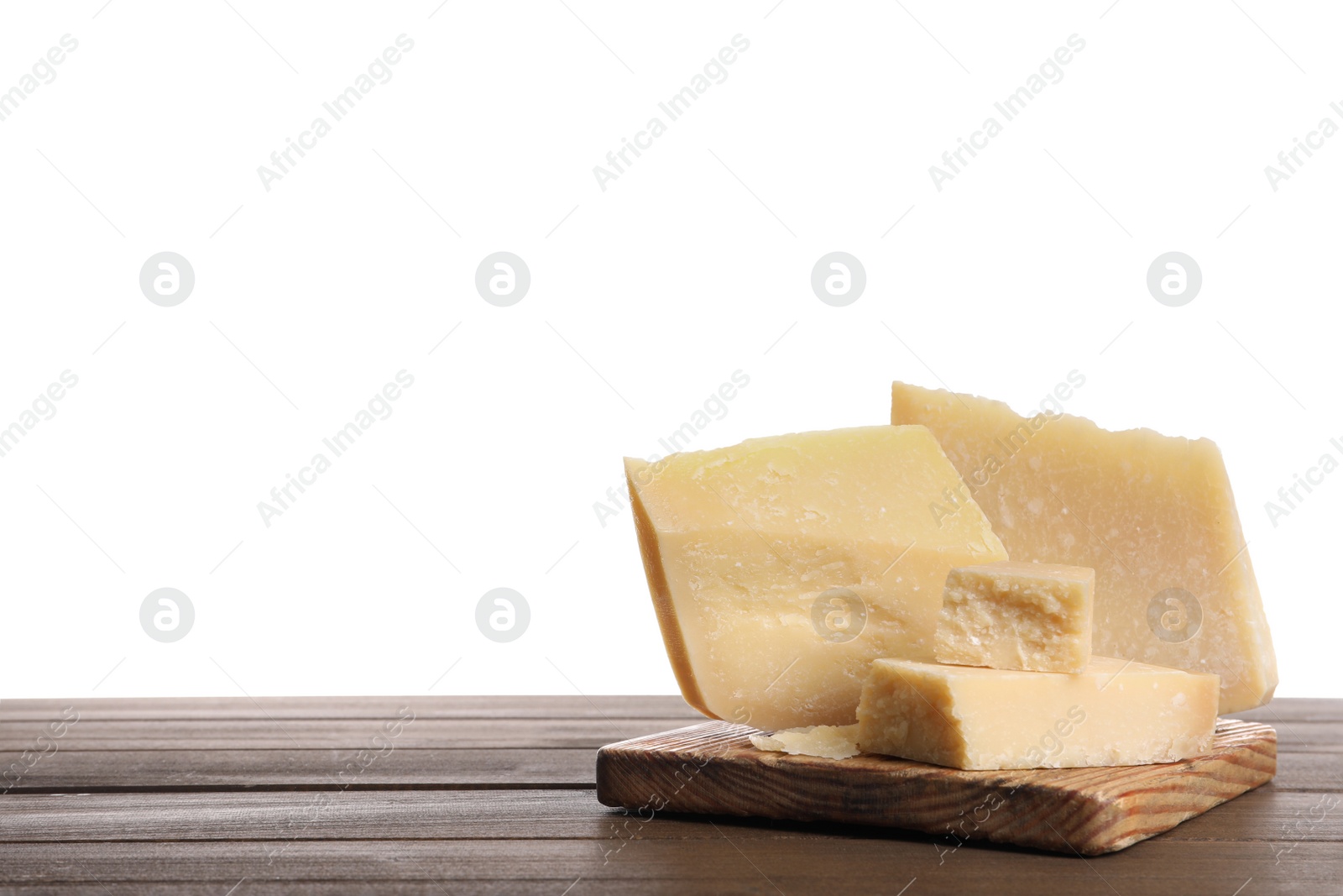 Photo of Pieces of delicious parmesan cheese on wooden table against white background. Space for text