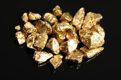 Pile of shiny gold nuggets on black background