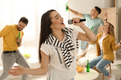 Photo of Young woman singing karaoke with friends at home