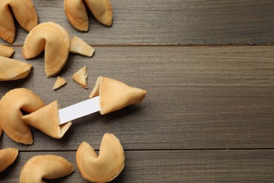 Photo of Tasty fortune cookies with predictions on wooden table, flat lay. Space for text