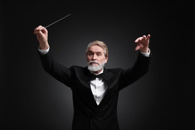 Professional conductor with baton on black background