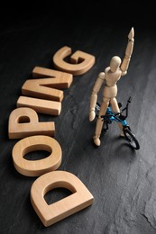 Photo of Word Doping, sportsman and bicycle model on black background