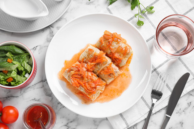 Photo of Delicious cabbage rolls served on white marble table, flat lay