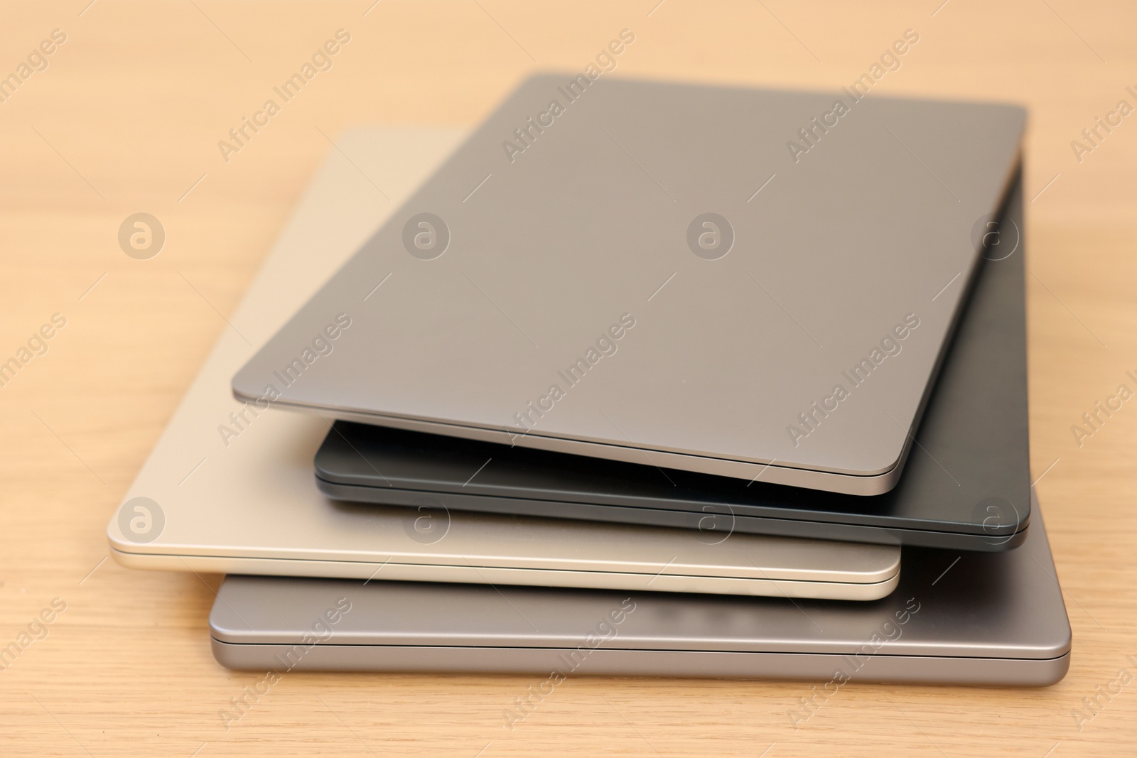 Photo of Different modern laptops on wooden table, closeup