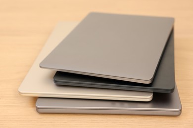 Photo of Different modern laptops on wooden table, closeup