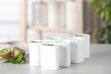 Photo of Cups for homemade yogurt and fresh kiwi on table in kitchen. Recipe for multi cooker