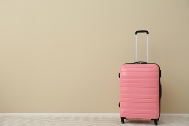 Photo of Modern suitcase on floor near light wall. Space for text
