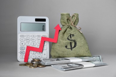 Photo of Economic profit. Money bag, coins, calculator, banknotes and arrow on light grey background